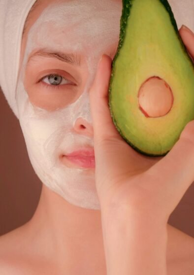 woman with white face mask holding green fruit